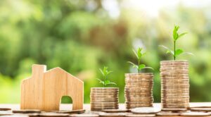 holzhausmodell-mit-geld-muenzenstapel